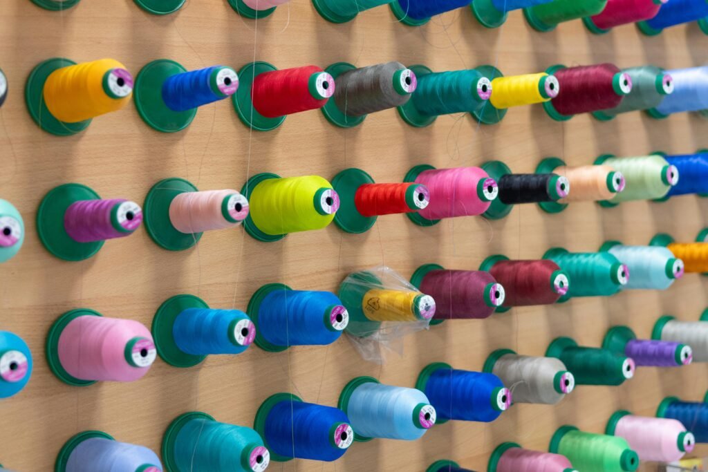 Vibrant colored thread spools neatly arranged on a display wall, showcasing creativity and organization.